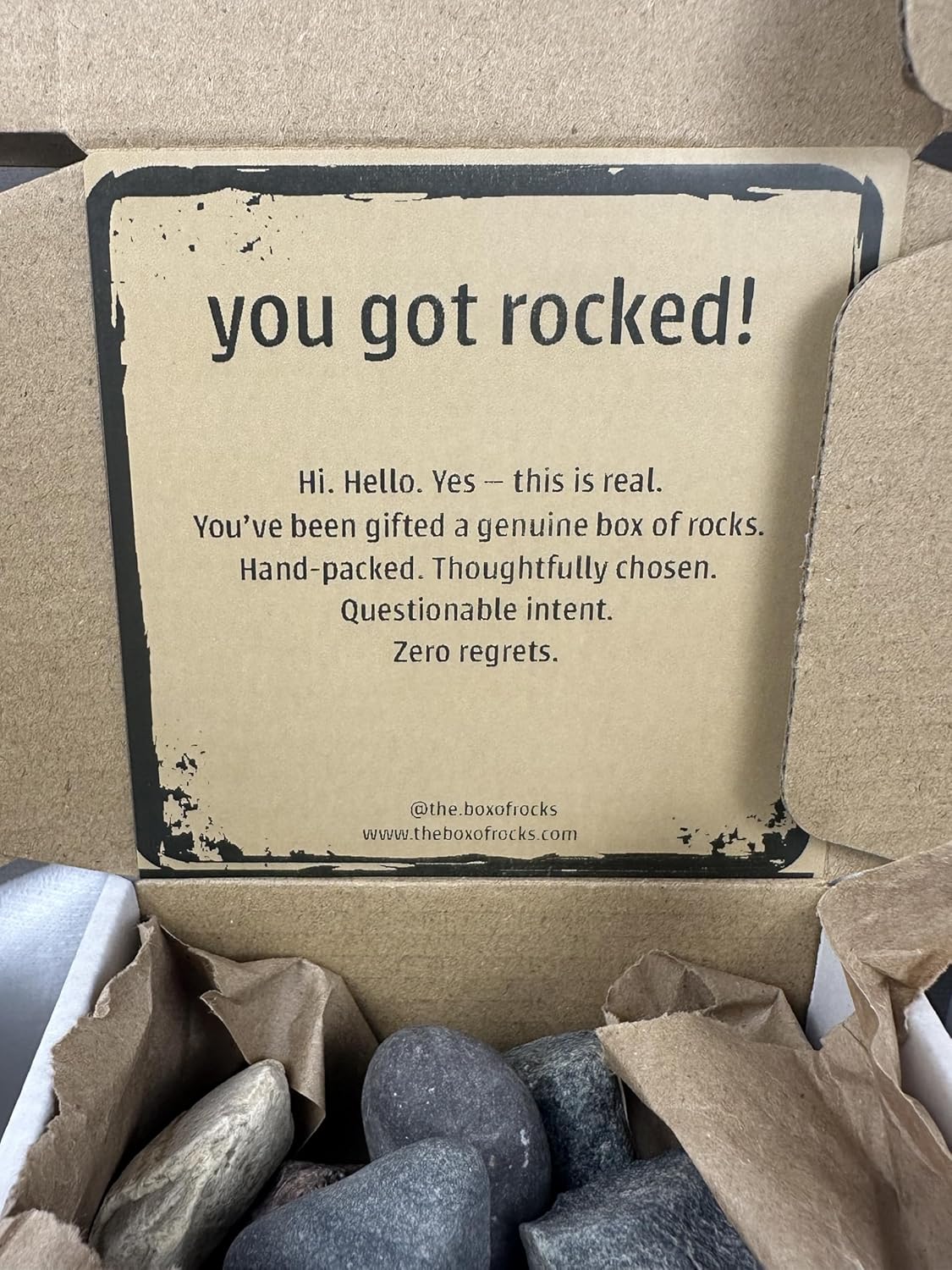 Close-up of The Box of Rocks with genuine river rocks and a You Got Rocked message
